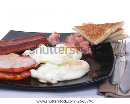 platter of scrambled eggs  ham  Sausages  bacon and toast bread.