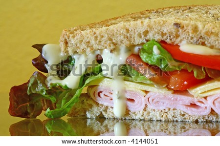wholebread sandwich with ham and cheese on brown background