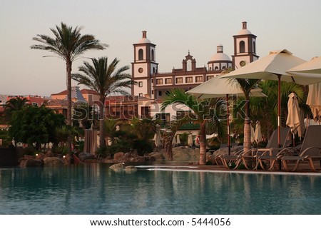 swiming pool at luxury hotel in spain with green palm and umbrellas
