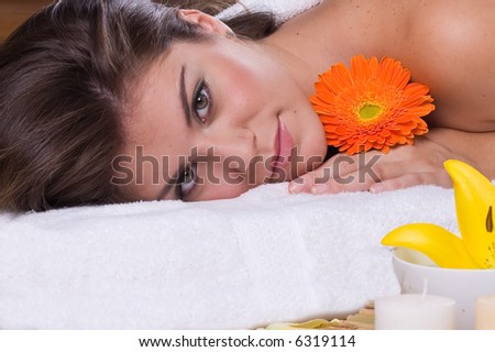 a beautiful woman relaxing in spa salon with flowers and candles