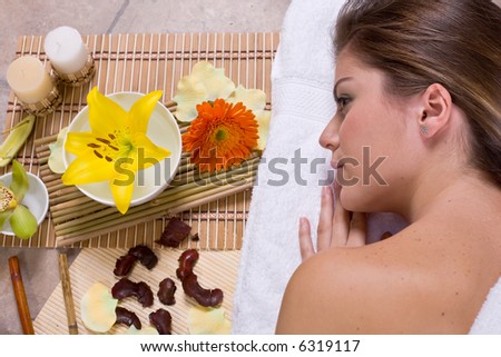 Beautiful young woman  relaxin in spa salon with flowers and candles