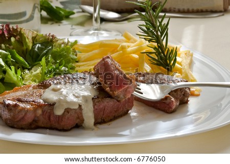 grilled beef steak with green salad and blue cheese sauce