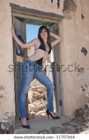 sexy young woman with blue jeans on old house under blue sky