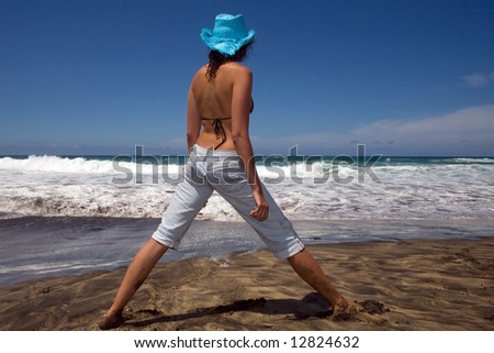 sexy young woman with bikini and jeans in the beach under blue sky