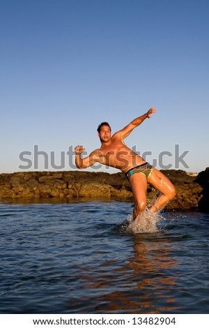 young athletic man jumping in the sea water