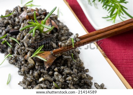 a white platter with rice and squid in ink on red background