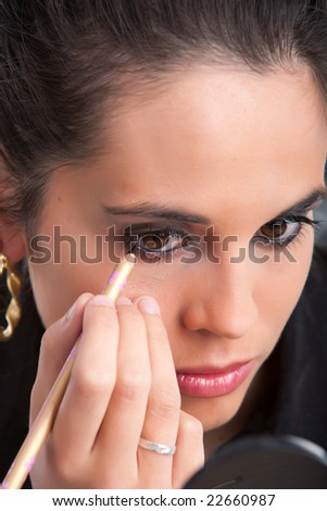 A woman touches up her makeup on face