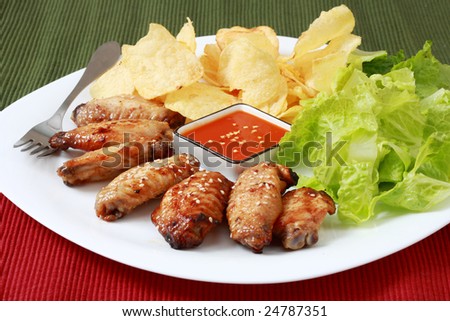 Grilled chicken wings with hot pepper sauce and salad