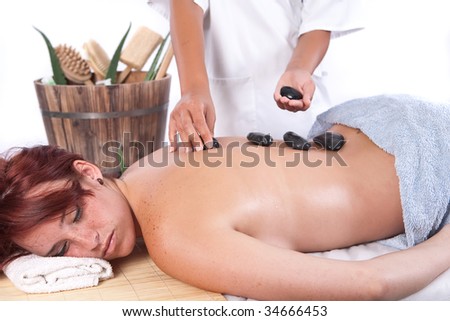 Red hair woman getting a stone massage in a spa