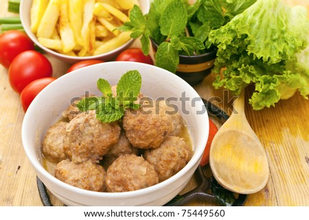 white bowl with beef meat balls with mint leaves.