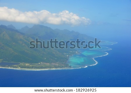 Aerial view of the island of Moorea with clouds, reef and lagoon. Moorea is an island near Tahiti in the tropical archipelago of French Polynesia inside the Pacific ocean.