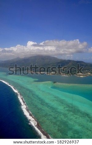 Aerial view of the island of Moorea with clouds, reef and lagoon. Moorea is an island near Tahiti in the tropical archipelago of French Polynesia inside the Pacific ocean.
