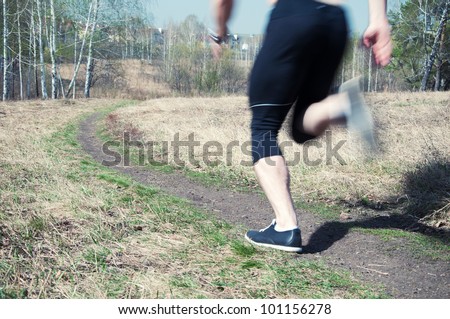 Low section of male athlete jogging outdoors, blurred motion
