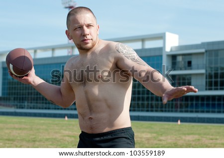 Shirtless male athlete winds up to throw an american football