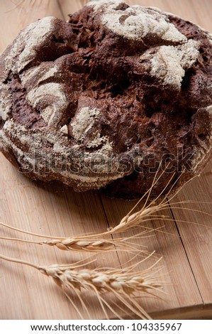 Whole wheat bread and shafts of wheat on a wooden board