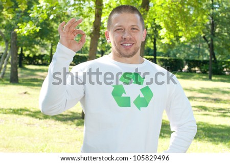 Smiling man with recycle logo on his shirt making OK gesture