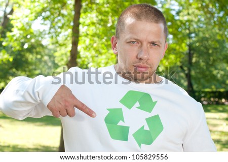 An adult serious man pointing at recycle logo on his shirt