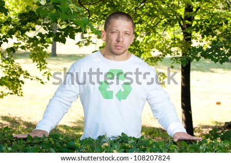 Ecologist with recycle logo on his shirt standing in green park