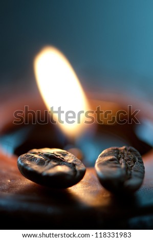 Burning aromatic coffee candle and roasted beans, macro, shallow DOF