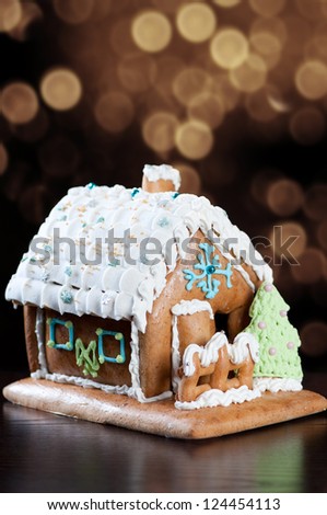 Vertical shot of a gingerbread house, glittery gold background
