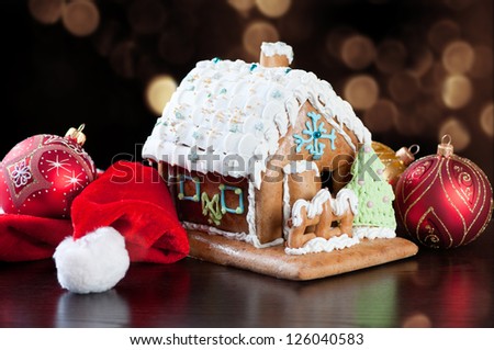 Gingerbread house, Santa hat and Christmas balls over glittery gold background