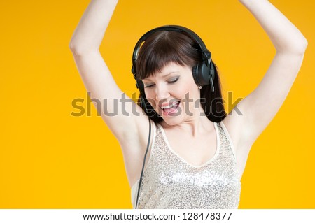 Carefree young woman in headphones listening to music and dancing, studio shot