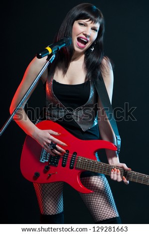 Expressive young woman holding electric guitar and singing