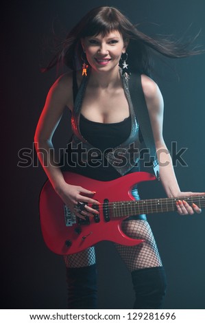 Female rock star playing the electric guitar, studio shot