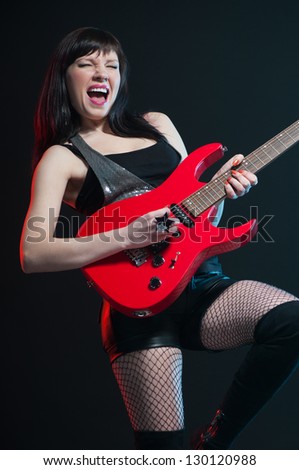 Expressive female rock star playing the guitar, studio shot