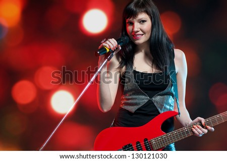 Female rock star with electric guitar over bright background