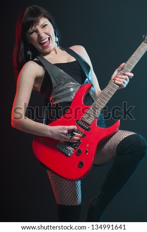Expressive female rocker playing the electric guitar, vertical shot
