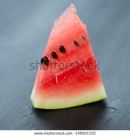 Slice of ripe and juicy watermelon on black wooden background