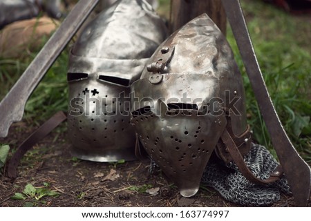 Two metal medieval helmets and swords, horizontal shot, close-up
