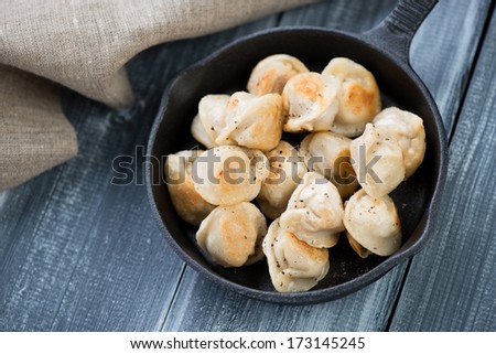 Fried pelmeni or meat dumplings, wooden background, above view