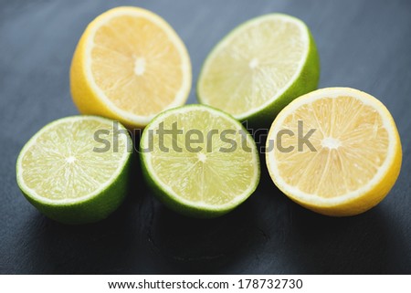 Fresh sliced limes and lemons, black wooden background