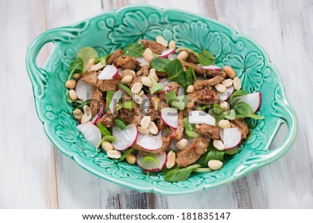 Salad with radish, roasted meat, corn salad leaves and peanuts