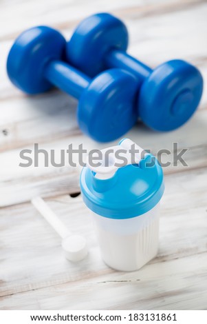 Protein shake with plastic dumbbells and a measuring scoop