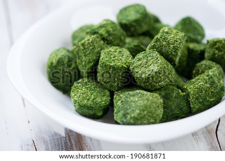 Cubes of chopped spinach in a glass plate, horizontal shot