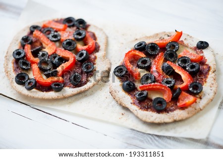 Mini pizzas with sliced red bell pepper, olives and parmesan