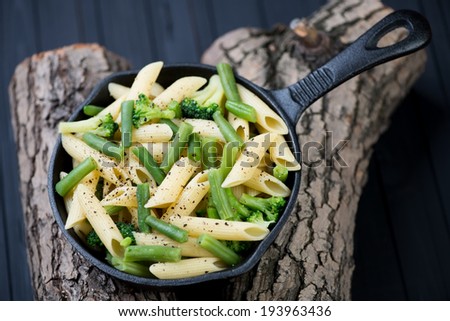 Frying pan with penne pasta and vegetables, above view