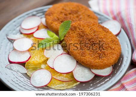Close-up of roasted fish burgers with oranges and radish