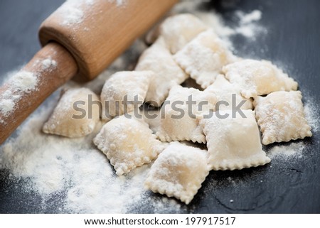 Raw cheese ravioli with flour and a rolling pin, horizontal shot