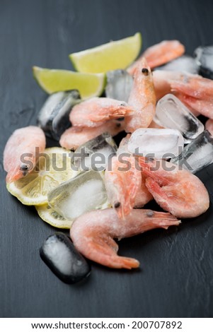 Frozen shrimps on ice cubes, close-up, vertical shot