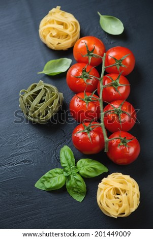 Above view of red tomatoes, green basil and pasta, vertical shot