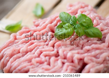 Close-up of minced turkey meat with green basil leaves, shallow depth of field