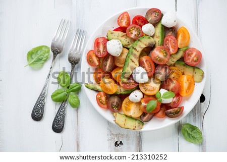 Vegetable salad with grilled avocado, tomatoes and mozzarella