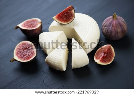 Sliced fig fruits and cheese, black wooden background, close-up