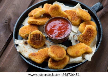 Frying pan with chicken nuggets and dip sauce, studio shot