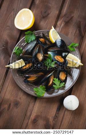 Mussels with lemon, garlic and parsley; rustic wooden background