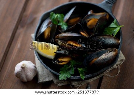 Boiled mussels with lemon, fresh parsley and garlic, close-up